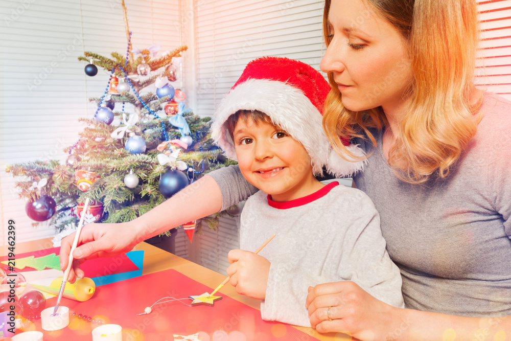 Boy preparing Christmas ornaments with his mom