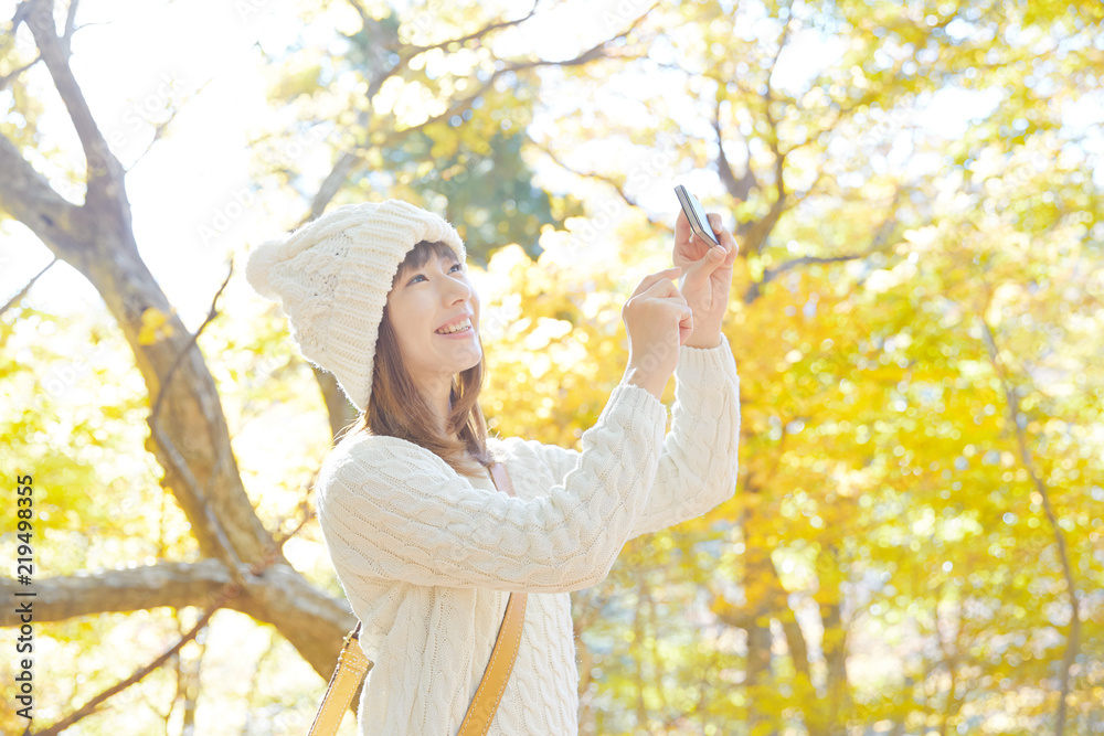 紅葉をスマートフォンで撮る女性