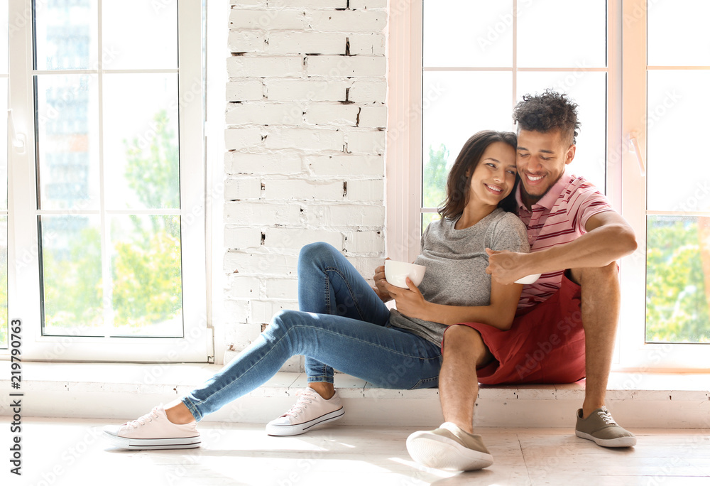 Happy African-American couple drinking tea at home