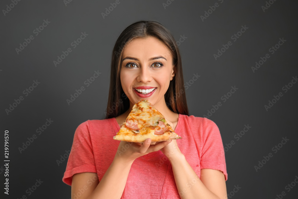 年轻女人吃着彩色背景的美味披萨片