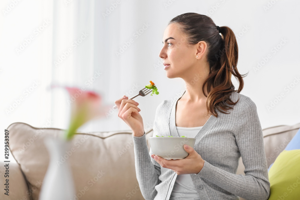 Young woman eating fresh salad at home. Healthy food concept