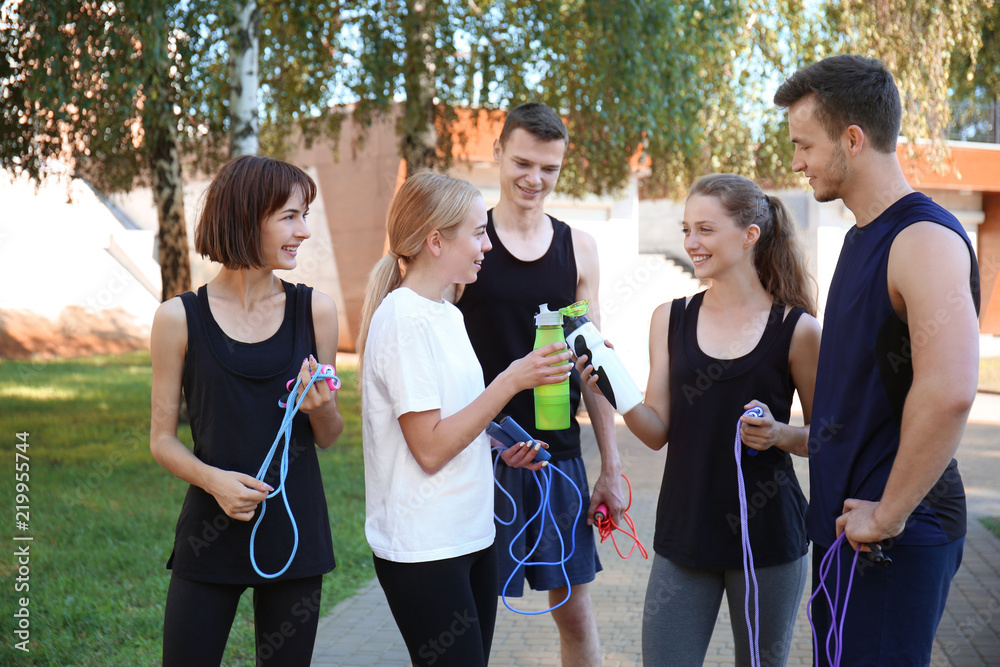 Group of young sporty people with jumping ropes outdoors