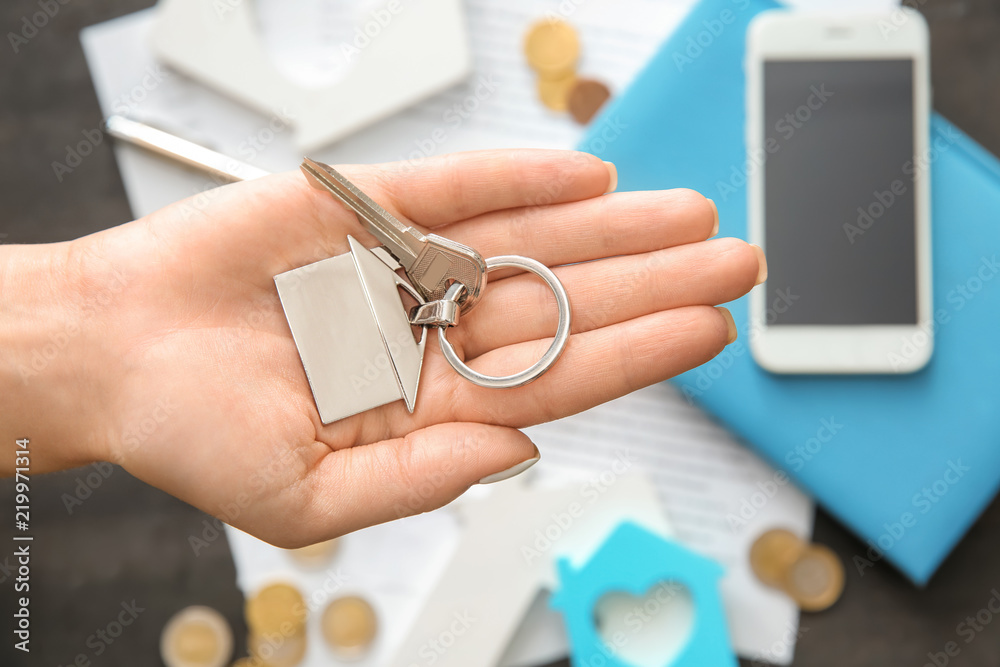 Real estate agent holding key with trinket in shape of house. Mortgage concept