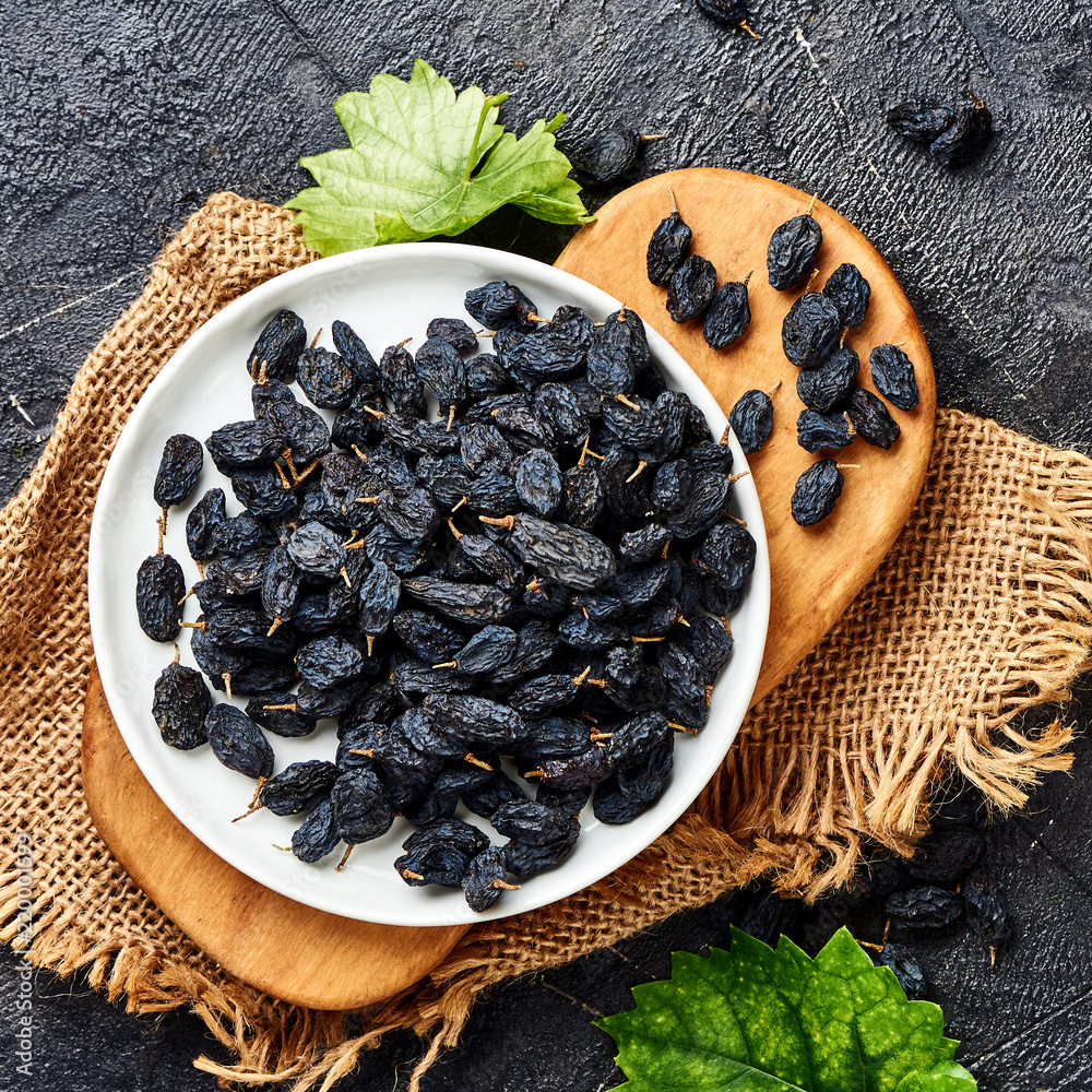 Black raisins on plate. Top view of dried grapes.