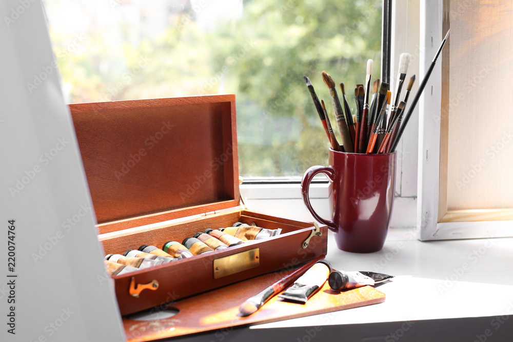 Set of brushes and paints on window sill in artists workshop