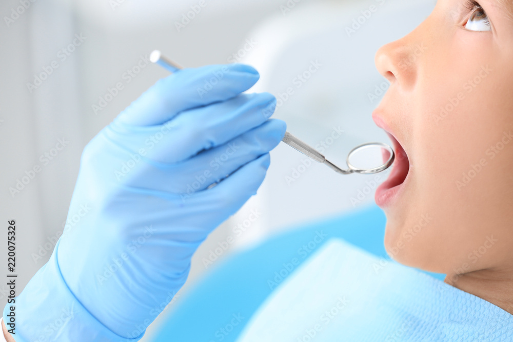 Dentist examining little boys teeth in clinic, closeup