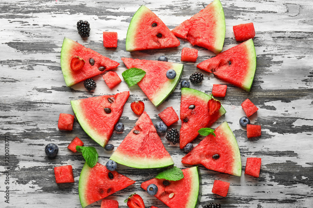 Sweet watermelon slices and berries on wooden background