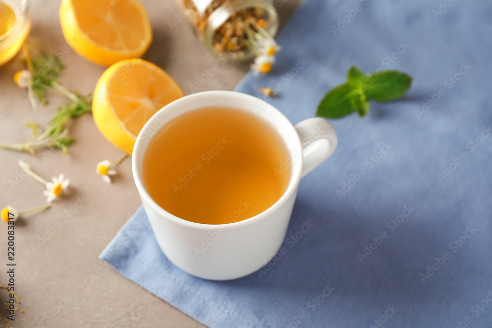 Cup of delicious camomile tea on light table