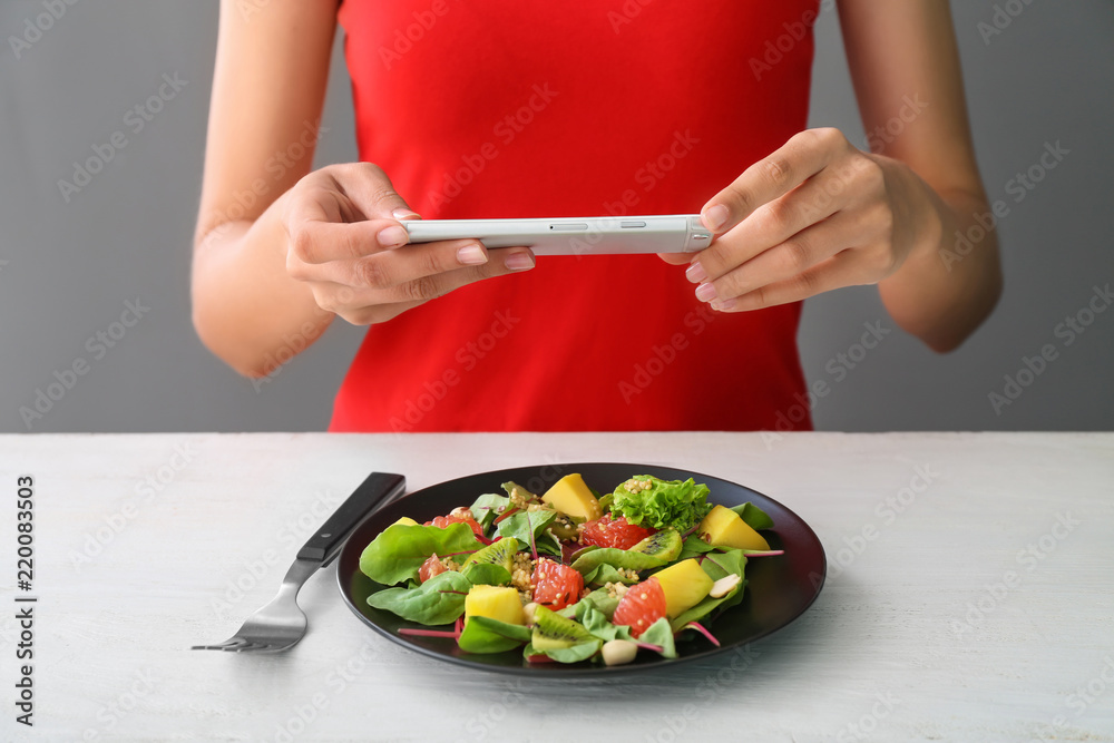 Woman taking photo of healthy salad with mobile phone