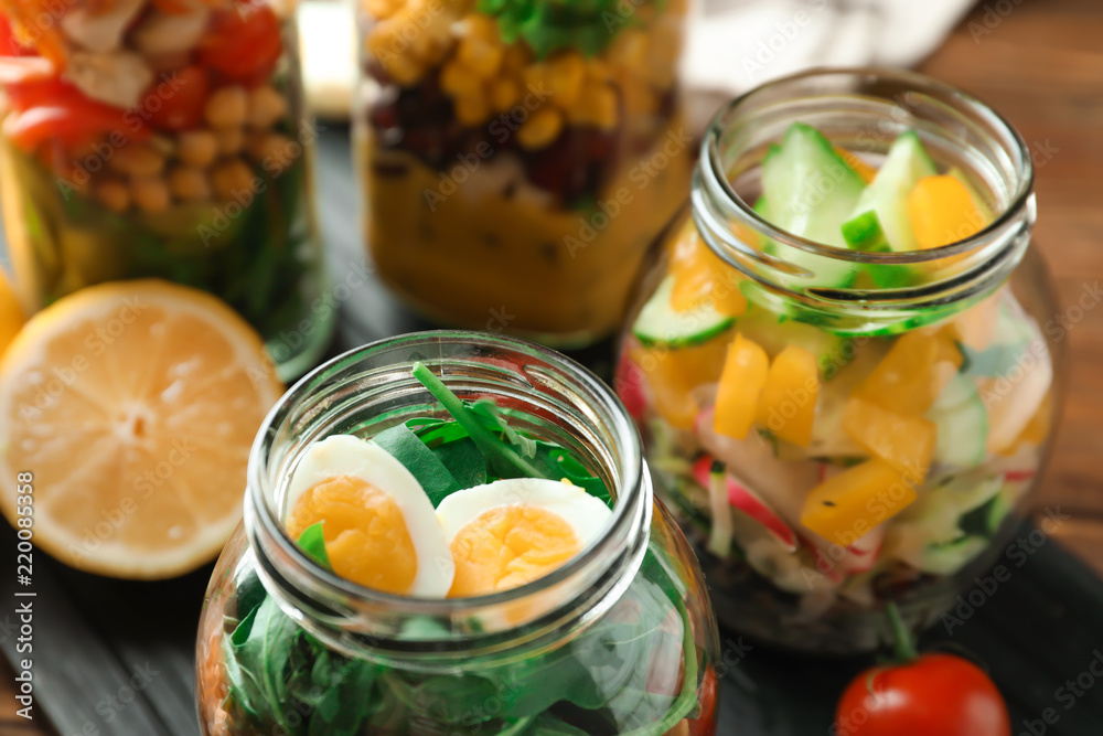 Delicious vegetable salads with egg in mason jars, closeup