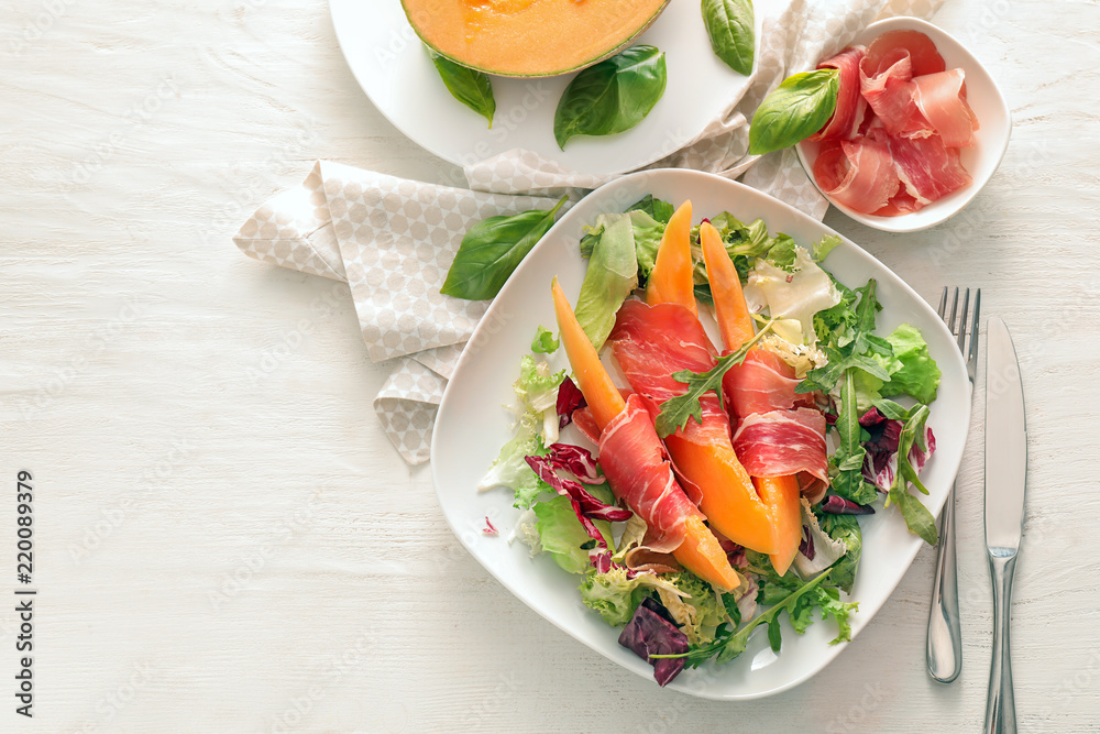 Delicious melon with prosciutto and herbs on light table