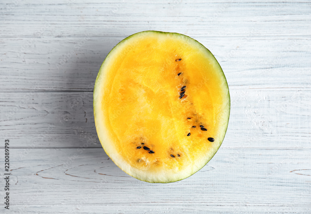 Half of yellow watermelon on white wooden background