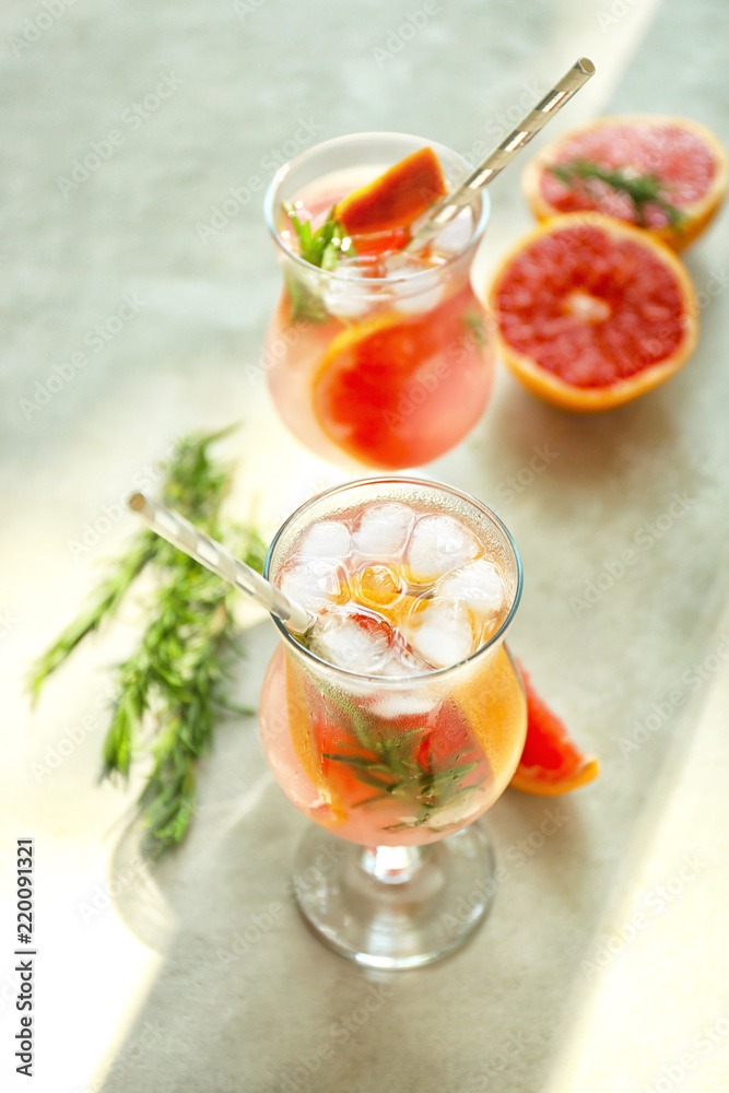 Fresh grapefruit cocktail with rosemary in glasses on light table