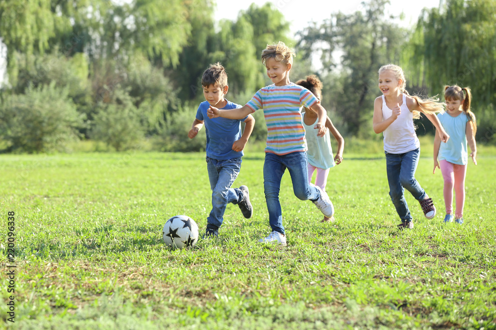 Cute little children playing football outdoors