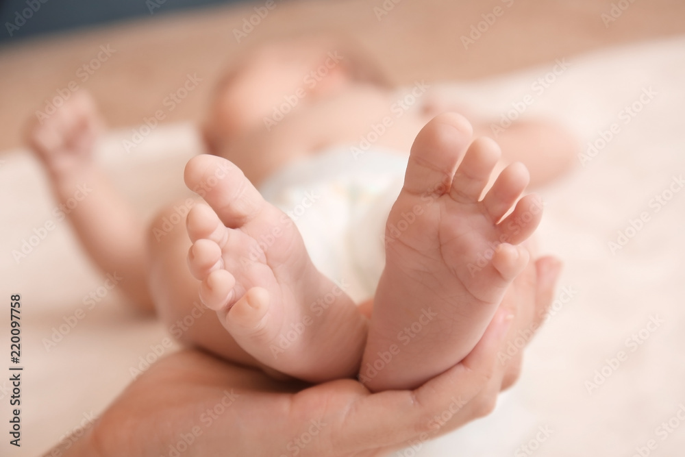 Mother holding feet of her baby, closeup