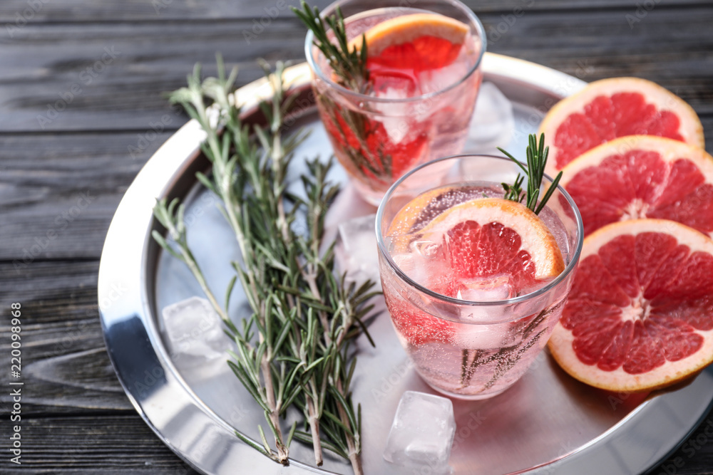 Fresh grapefruit cocktail with rosemary in glasses on metal tray