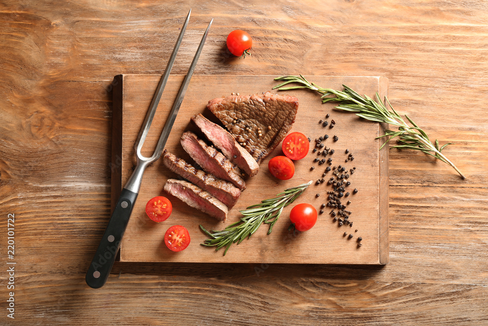 Cut grilled steak with tomatoes and spices on wooden board