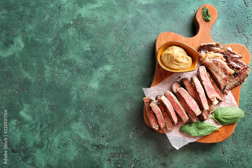 Cut grilled steak with sauce on wooden board