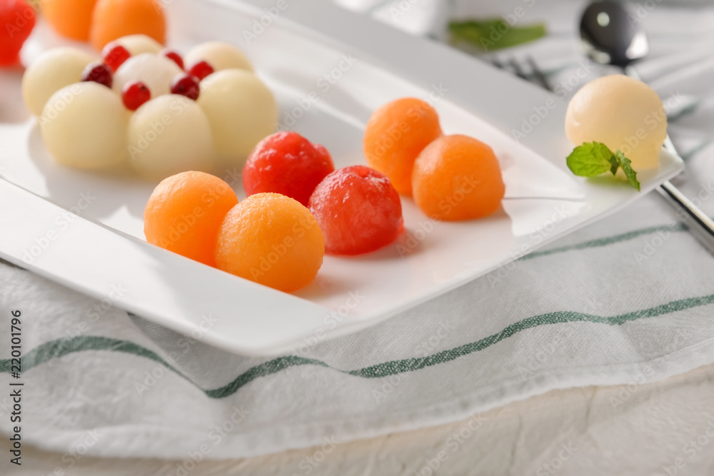 Plate with tasty melon balls on table