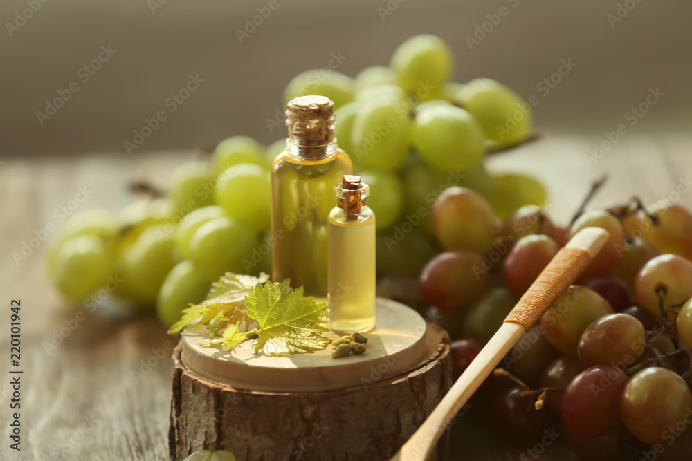 Bottles with grape seed oil on wooden stand