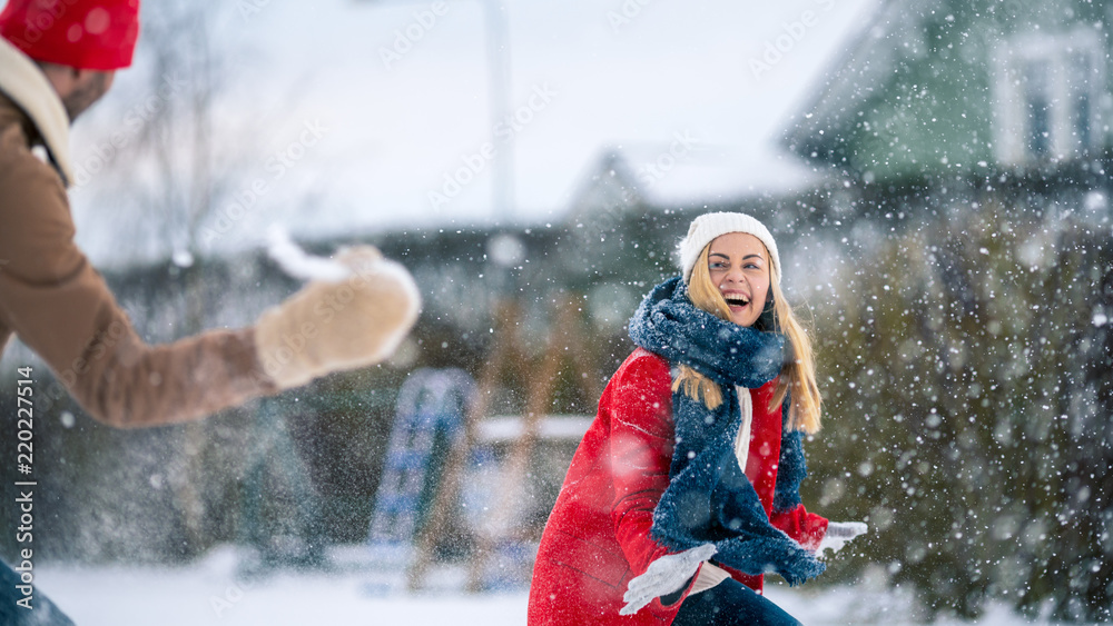 年轻漂亮的情侣在下雪时互相扔雪。快乐的男人和女人在一起玩