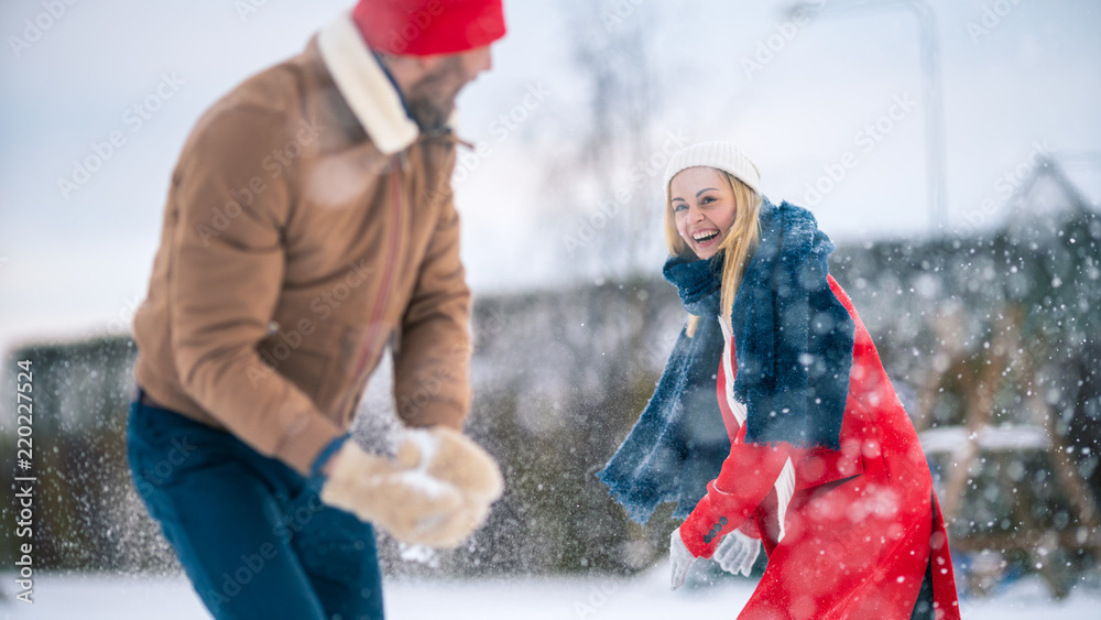 年轻漂亮的情侣在下雪时互相扔雪。快乐的男人和女人一起玩