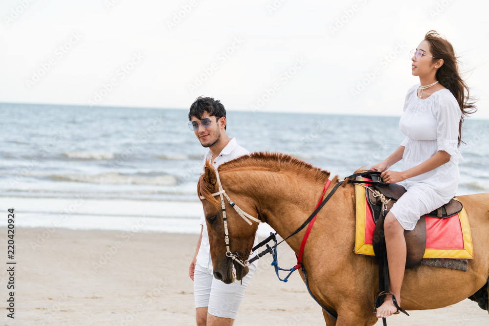 年轻夫妇在热带海滩上骑马。