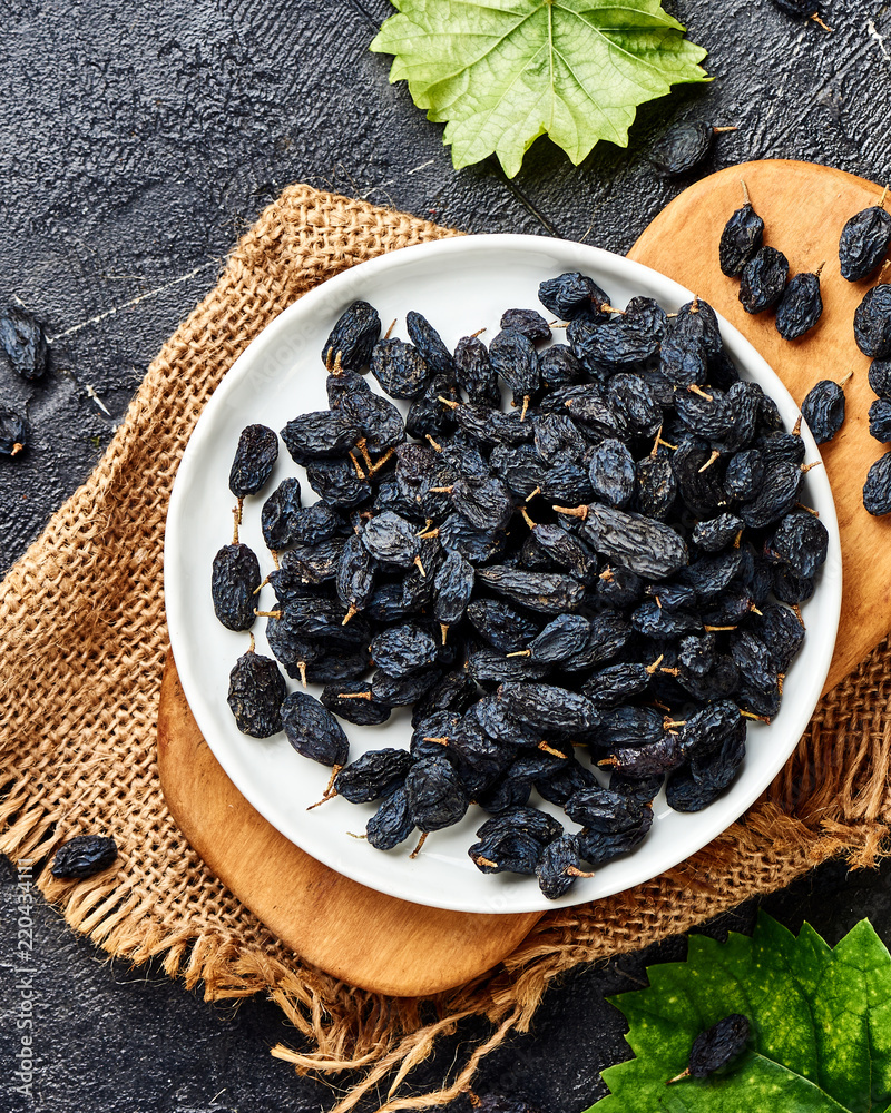 Black raisins on plate. Top view of dried grapes.