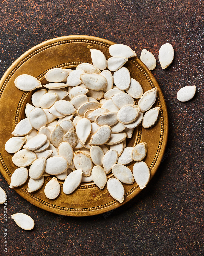 Raw pumpkins seeds on brown background. Top view.