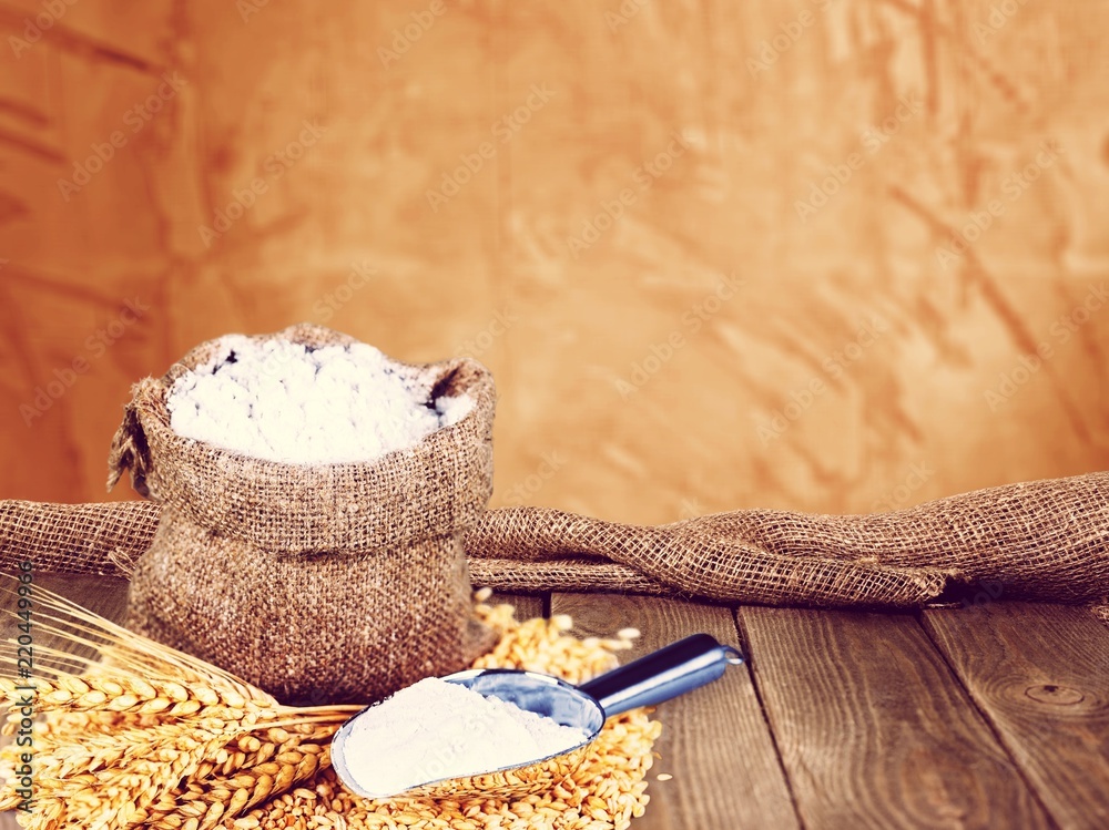 Sack of flour with wheat and scoop isolated on white background