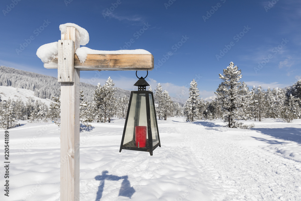 Lantern marked winter hiking trail leads through a fresh snowy landscape in Switzerland