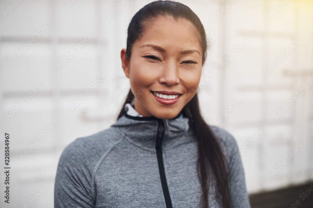 站在外面微笑的穿着运动服的亚洲年轻女子