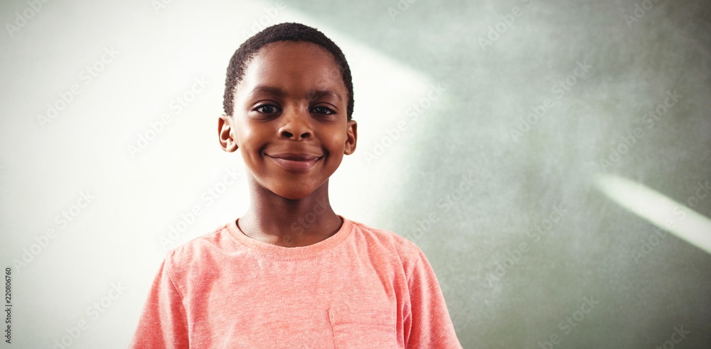 Smiling boy holding cellphone against greenboard