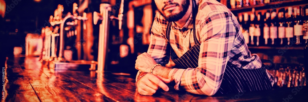 Portrait of waiter leaning at counter 