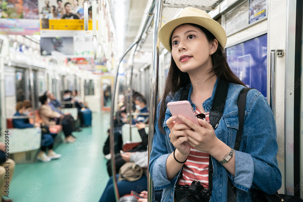 girl using phone and standing in moving train