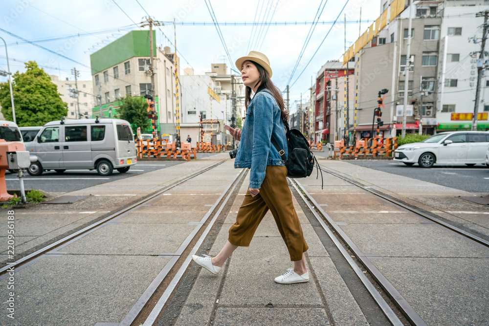 一个拿着电话穿过铁路的女人