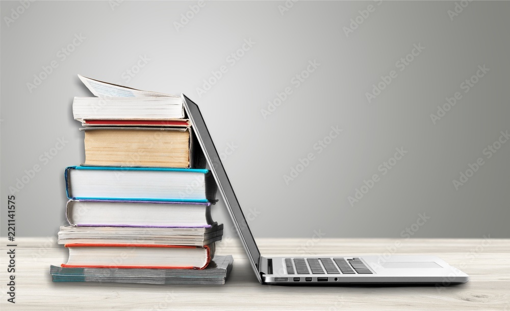 Stack of books with laptop on table