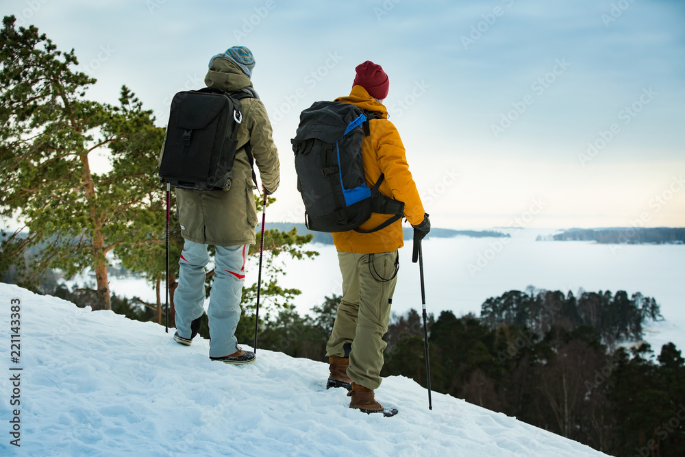 两个成熟的男人在冬天探索芬兰。旅行者徒步旅行并用相机拍照