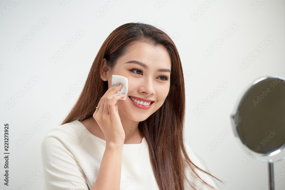 美丽的女孩用化妆棉清洁面部