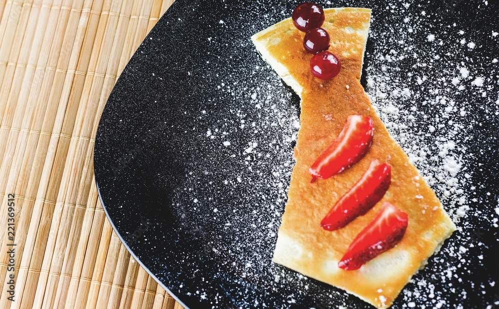 Cake with pieces of strawberry and cherries on black plate with