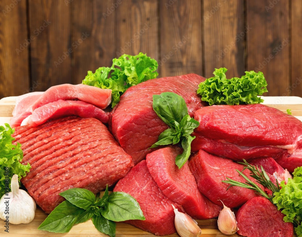 Fresh raw meat with vegetables on brown wooden table at wooden