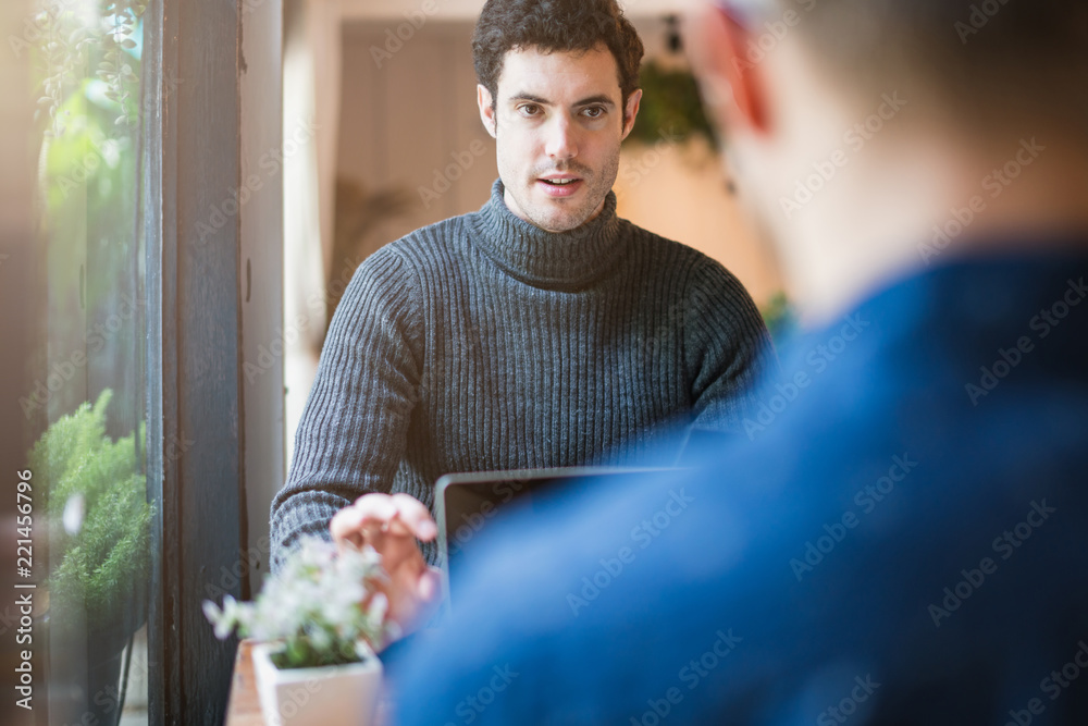 两个聪明的白人男子在窗口咖啡馆附近会面并进行严肃而专注的交谈