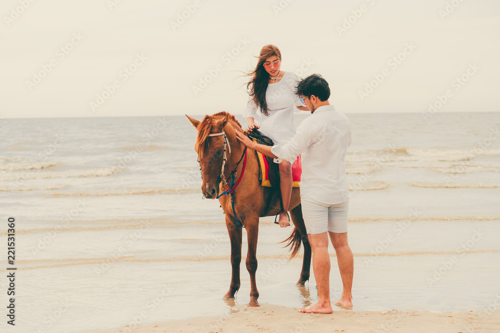 一对年轻夫妇在热带海滩上骑马。