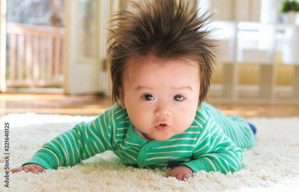 Happy newborn baby boy playing on the carpet