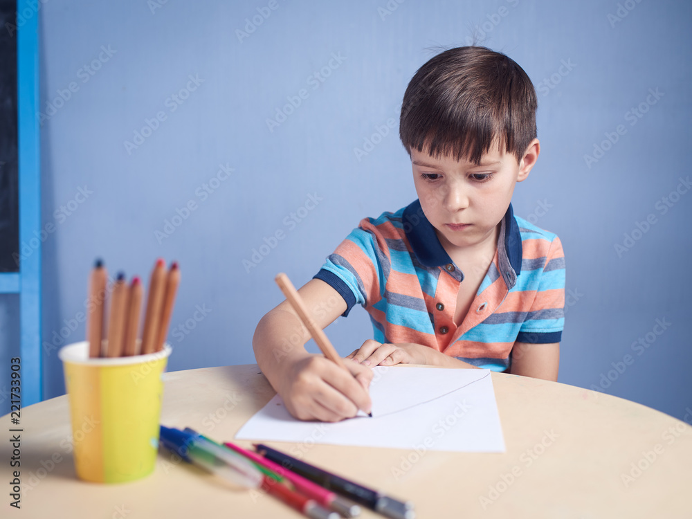 Caucasian boy spending time drawing with colorful pencils at home.