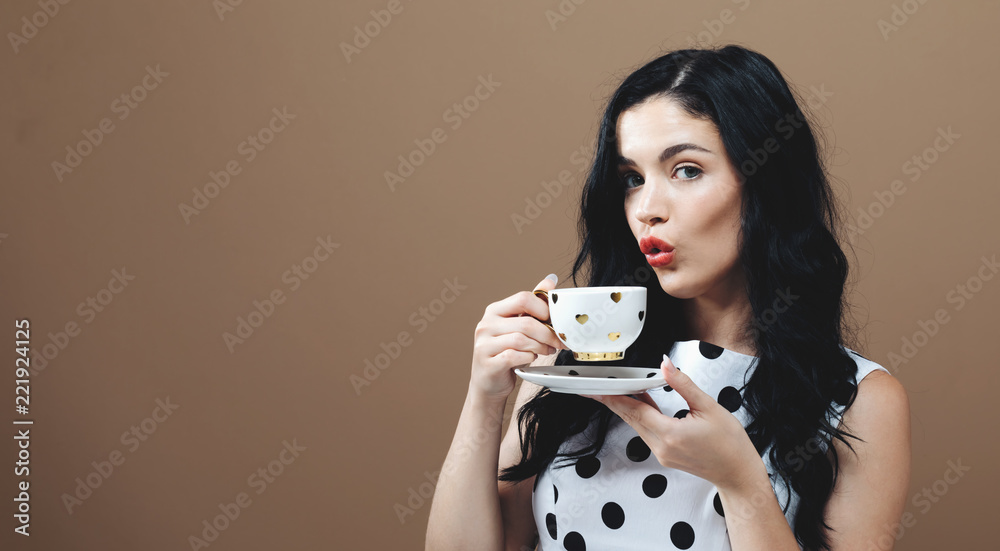 Young woman drinking coffee on a solid background