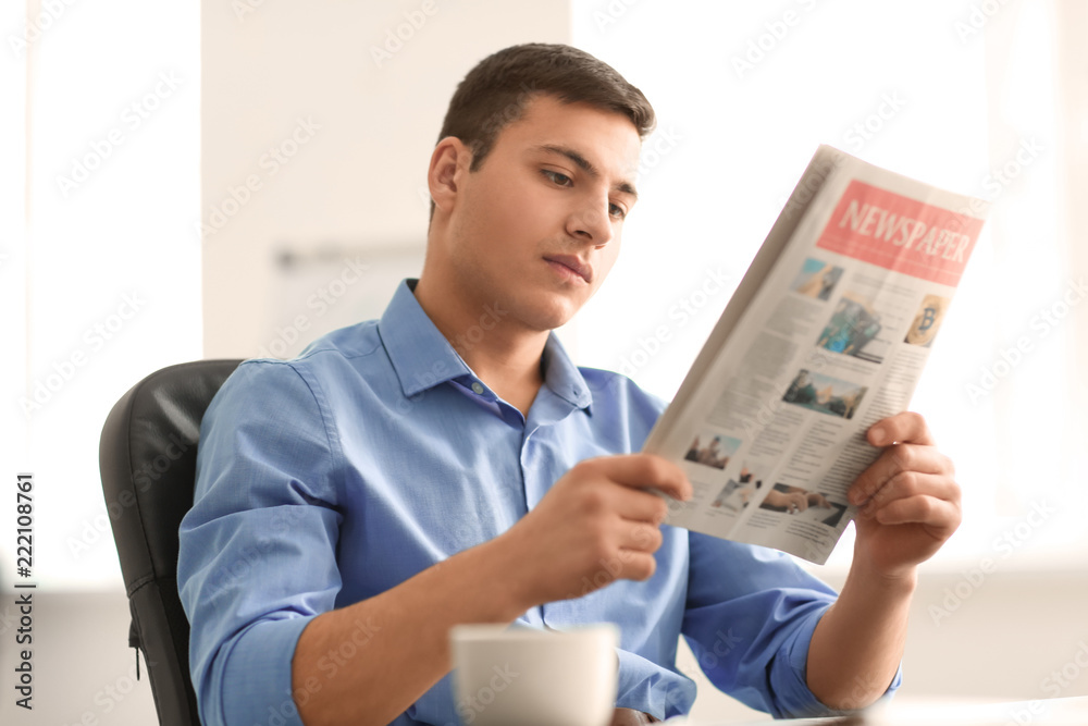 Handsome businessman reading newspaper in office