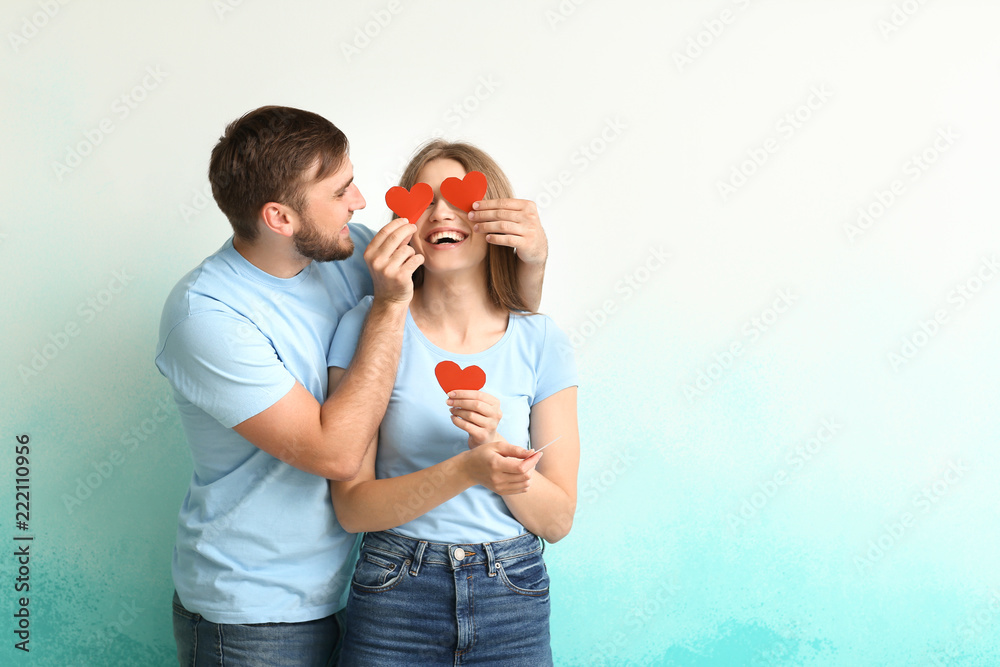 Happy young couple with red hearts on color background