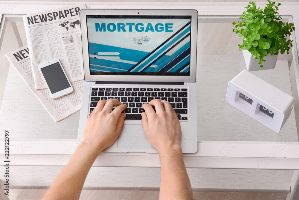 Man using laptop to pay mortgage loan online at home