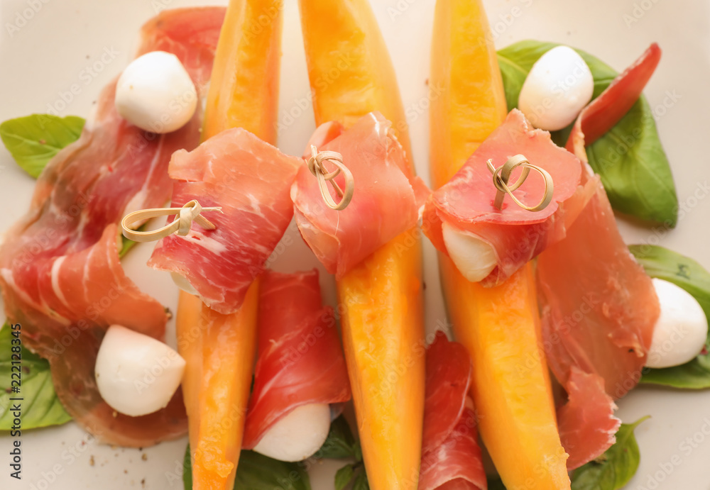 Delicious melon with prosciutto and mozzarella cheese on plate, closeup